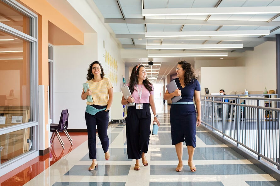 Alt text: Three teachers walk down a school hallway